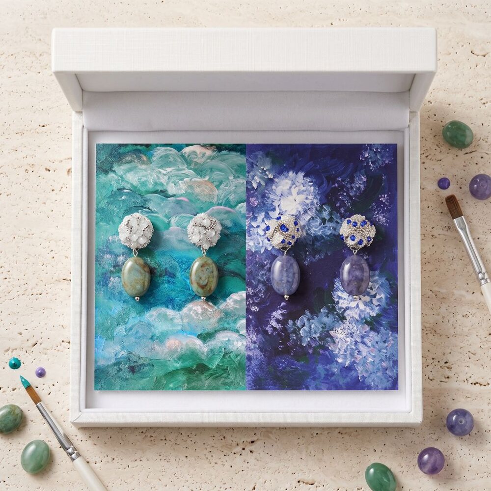 Handmade drop earrings in a jewellery box, surrounded by paintbrushes and gemstones