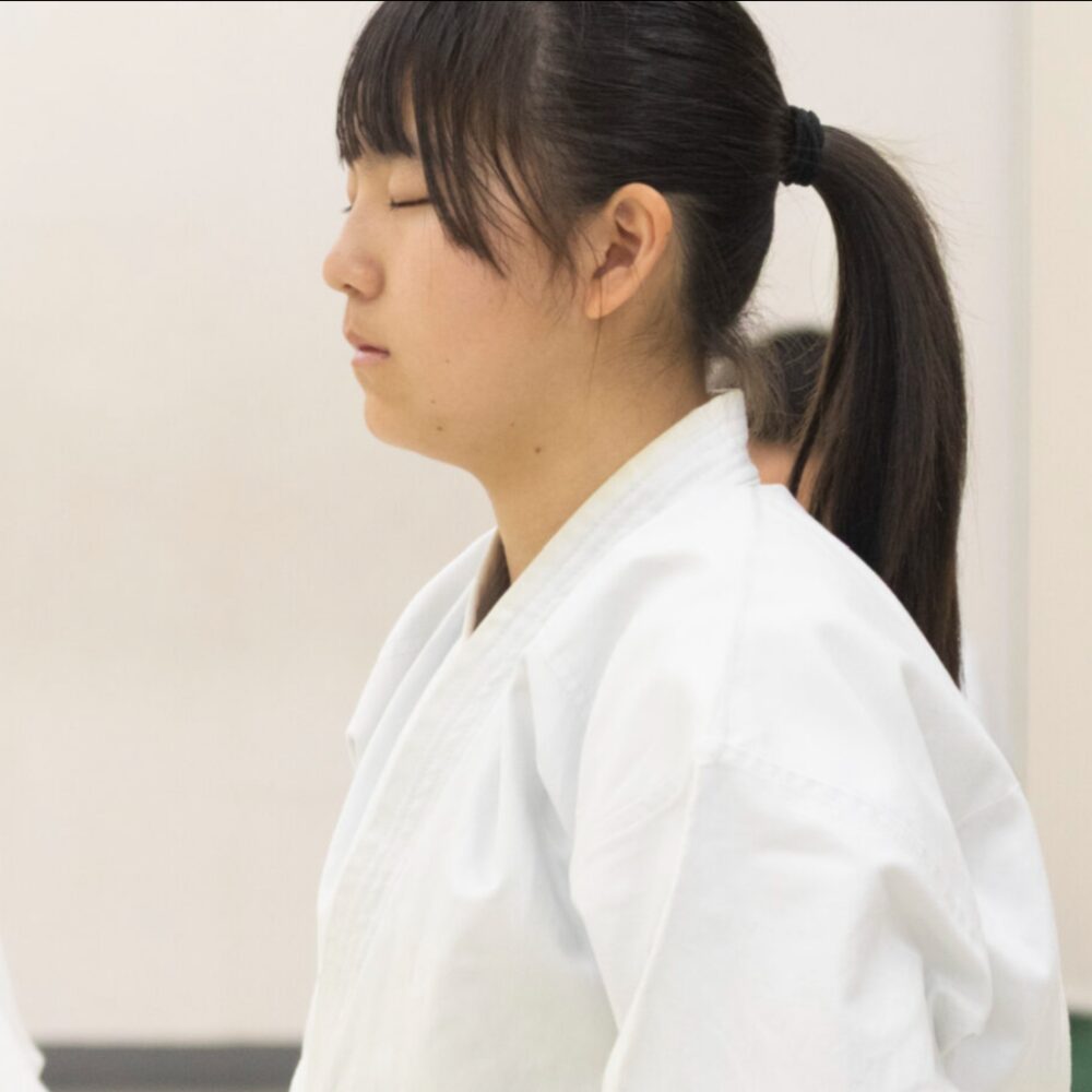白い道着で目を閉じ、集中する空手家の横顔